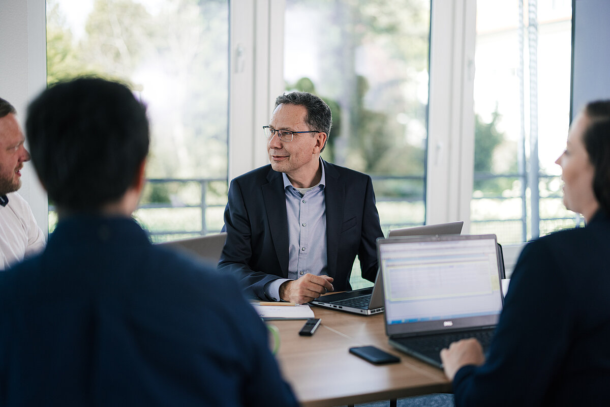 Berater bei einer Besprechung bei Dynamity, die Daten analysieren und Geschäftsprozesse mit Laptops in einem modernen Büro gemeinsam diskutieren.