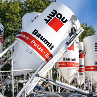 Baumit Produktionssilos und Baustoffanlagen auf einem Industriegelände, die die Kompetenz des Unternehmens für moderne Baustofflösungen zeigen.